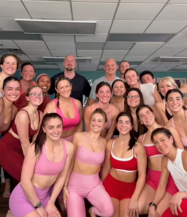 An indoor class packed with people in pink and red